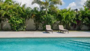 Poolside loungers surrounded by lush tropical gardens at Novara 202 vacation rental in Cozumel