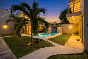 Tropical garden and illuminated common pool at night at Sophie’s Loft in Cozumel